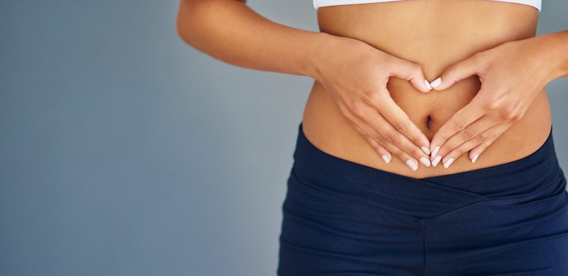 A woman making a heart shape on the stomach.