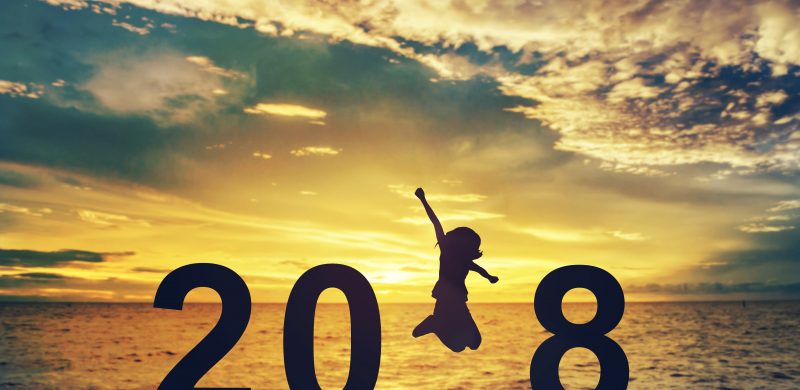 Silhouette young woman jumping on the sea and 2018 years while celebrating new year
